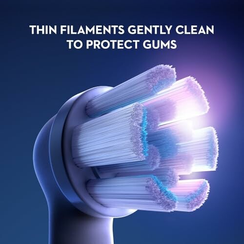 Close-up of toothbrush head with thin filaments and protective gum text.